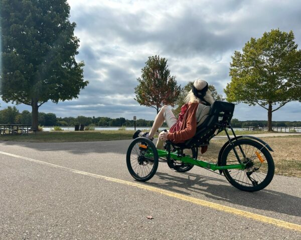Adaptive cyclist riding a recumbent trike along a scenic path