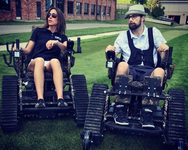 Two people in all-terrain track chairs outdoors